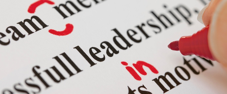 Close-up of printed text with red pen markings correcting words, focus on editing and proofreading